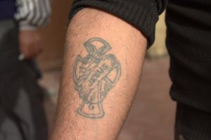 A man shows his Christian tattoo in the grounds of the cathedral (photo by Patrick Keddie)