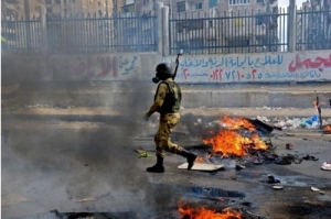 An Egyptian soldier walks through a burning street in Alexandria after clashes with supporters of ousted President Mohammed Mursi